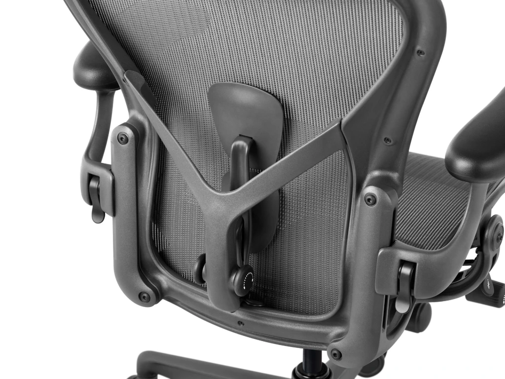 Herman Miller Aeron Chair Herman Miller Aeron office chair in graphite at a three-quarter angle from the back, a performance chair covered by the 12-year, 3-shift warranty